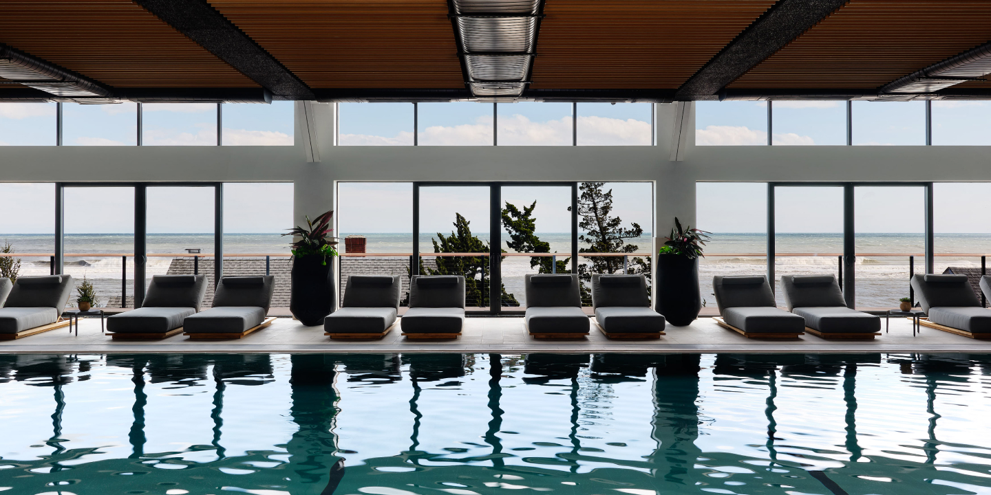 Indoor pool area with lounge chairs, large windows, and ocean view.